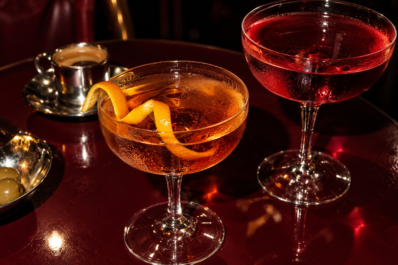 Amber and ruby cocktails on a burgundy café table